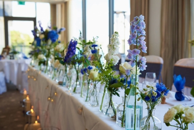 Top table arrangement of blue and white simple flowers in bottles