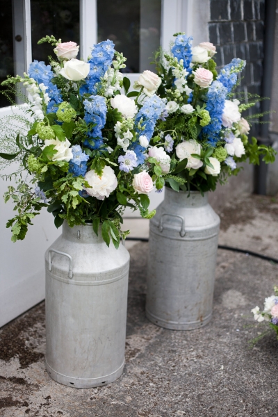 Milk churns filled with summery delphiniums, roses etc
